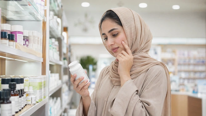 امرأة تبحث عن منتجات تسمين الوجه من الصيدلية مثل الكريمات والكولاجين والفيتامينات