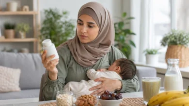 أم مرضعة تحمل رضيعها وتنظر إلى عبوة مكمل لزيادة الوزن مع أطعمة مغذية على الطاولة